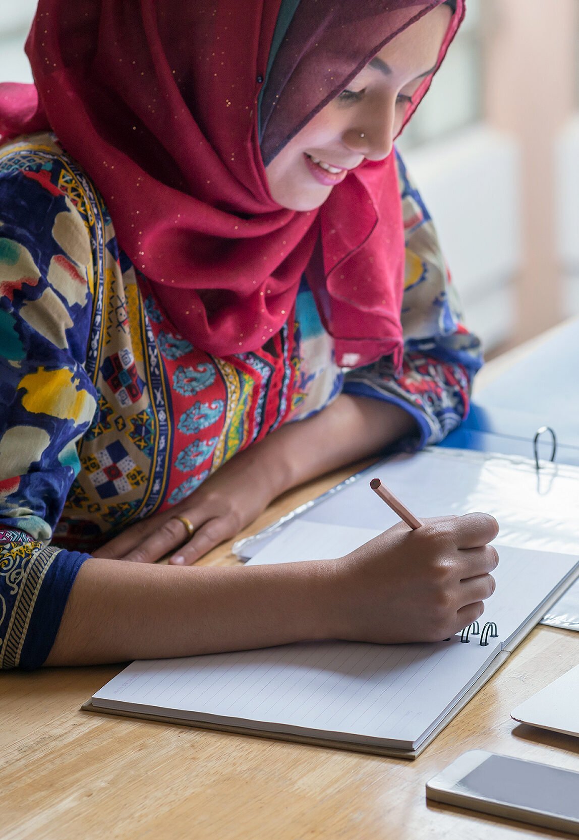 Muslim woman working with computer and writing notebook.