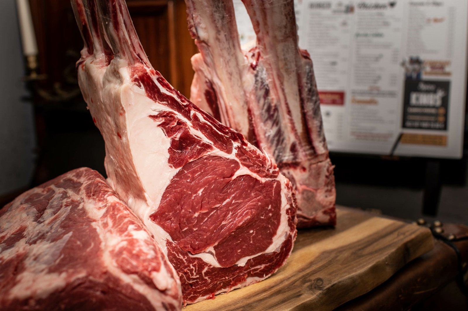 Tomahawk Steaks dryaged auf Holzbrett im Restaurant mit Metrofliesen